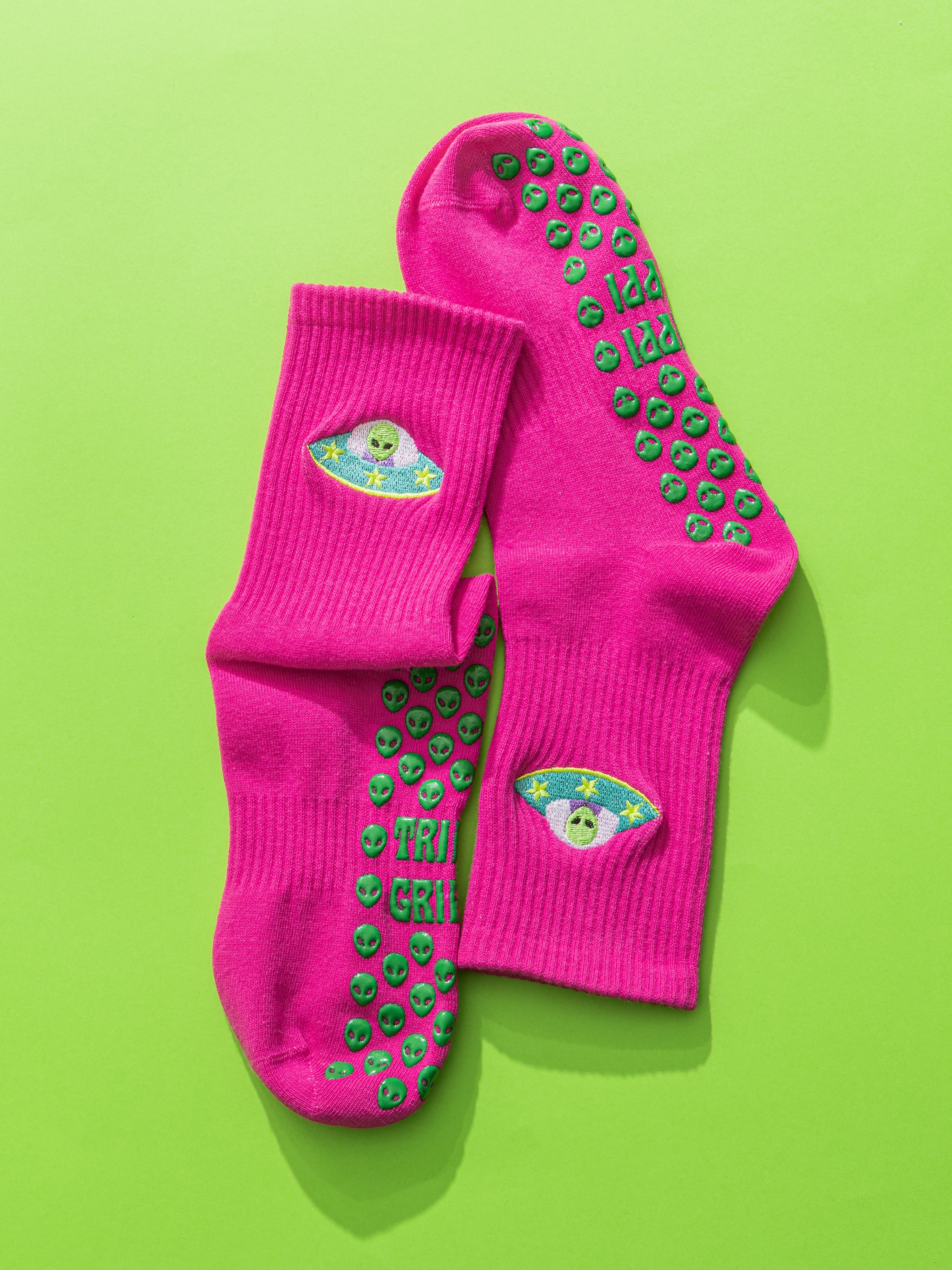 Pink socks with green slip-resistant alien grips on a green background. Slip-resistant socks for pilates, barre, lagree or yoga.